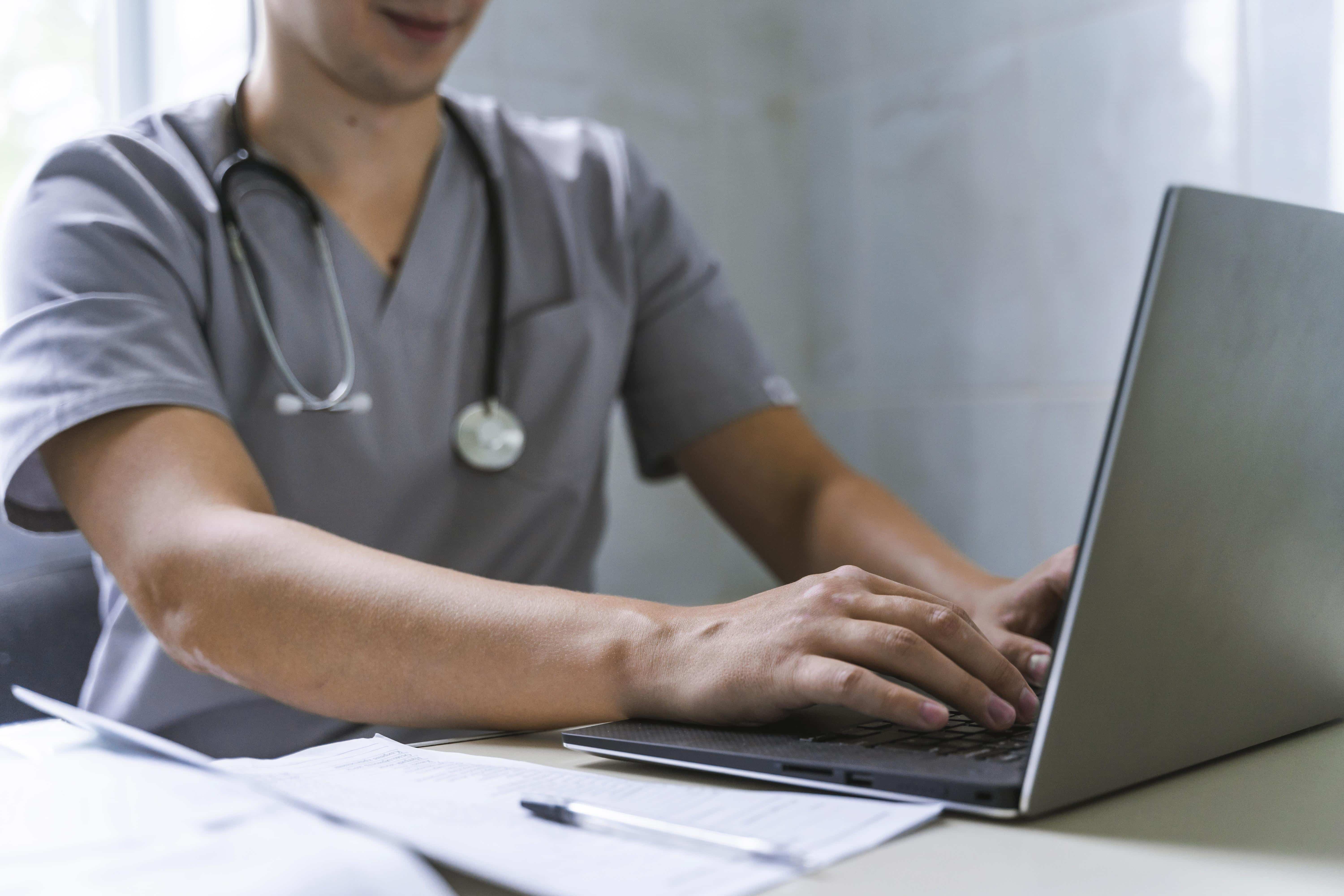 side view doctor with stethoscope working laptop